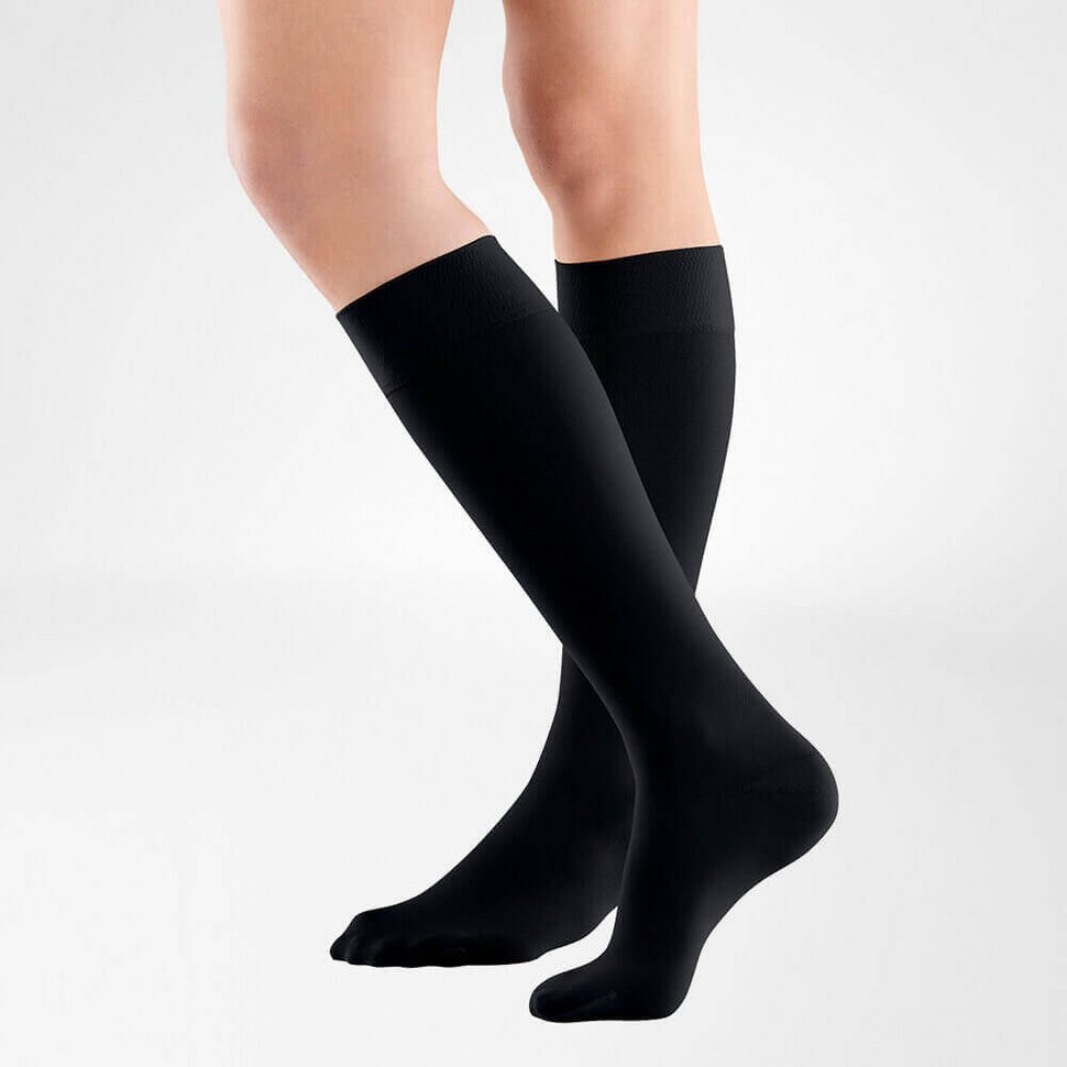 Black knee-high socks worn by a person on a light gray background