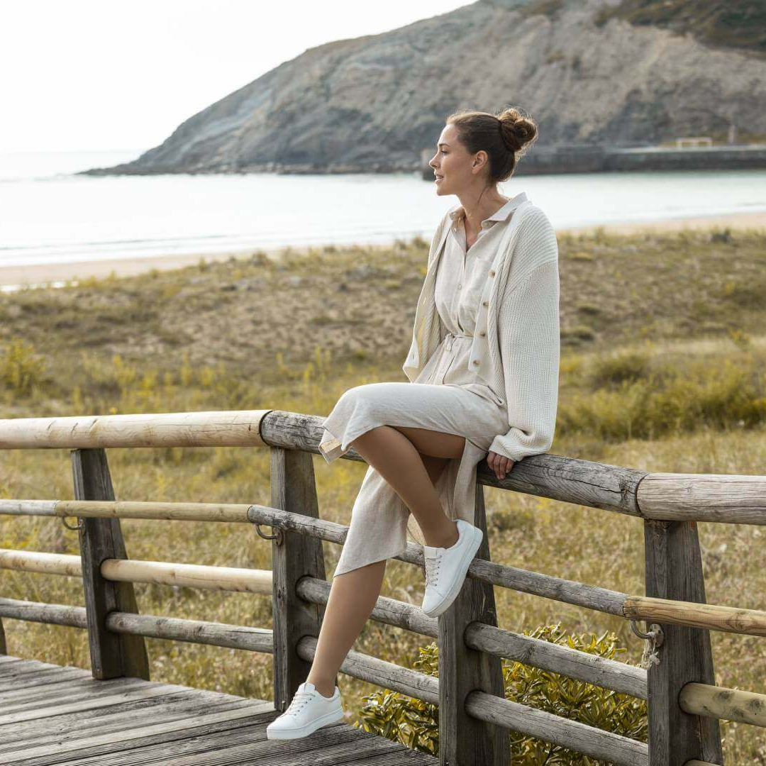 Woman sitting on a wooden railing by a scenic lakeside wearing bauerfeind medical venotrain soft s compression stockings in color cashew