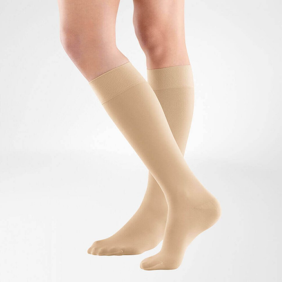 the knee high bauerfeind medical venotrain soft compression stockings in color cream worn by a person on a white background